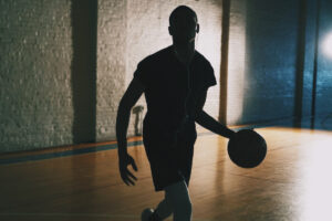 Flooring Specifier's Fixed Resilient Resources - man on basketball court dribbling ball. 