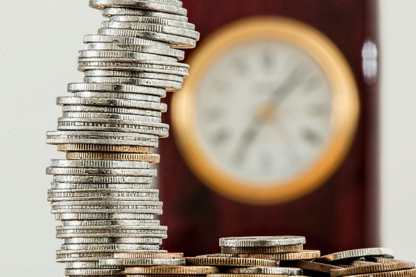 a stack of coins with a blurred out clock in the background