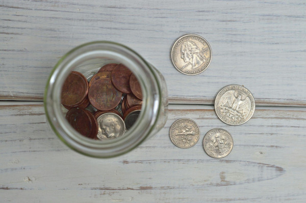 How to Fundraise Image - looking down into a jar of coins with coins laying on the table next to the jar